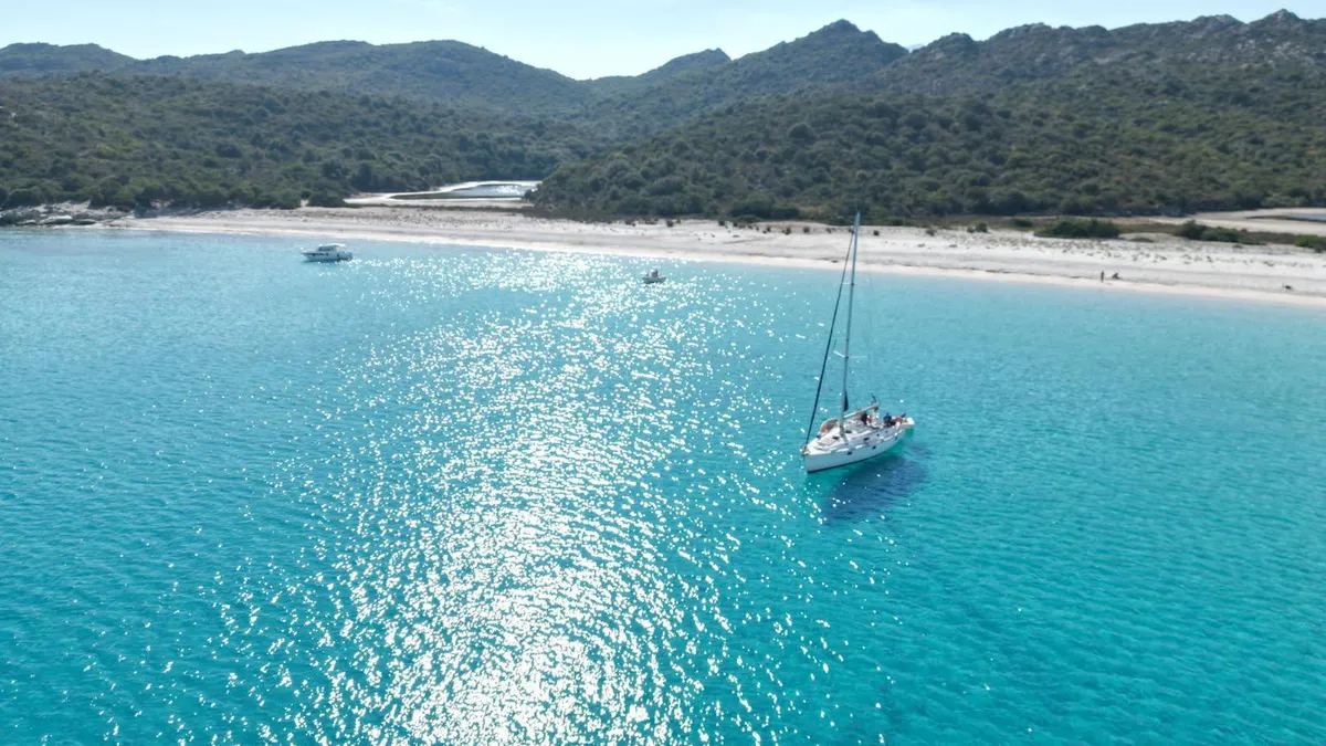 Voilier au mouillage devant la plage du Lotu aux Agriates, eau turquoise cristalline
