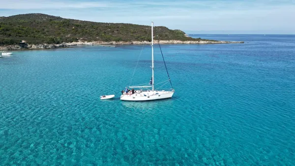 Voilier au mouillage avec annexe dans une anse turquoise